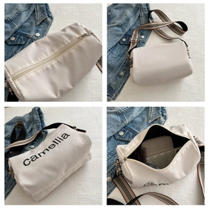 Detail view of cream canvas crossbody bag with striped strap and black Camellia text