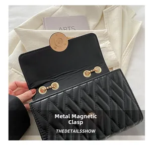 Détail du fermoir magnétique doré et texture matelassée en V sur le sac à chaîne