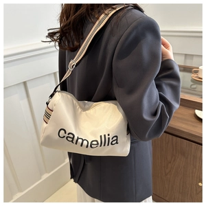 Detail of camellia nylon puffer bag with adjustable striped shoulder strap on model