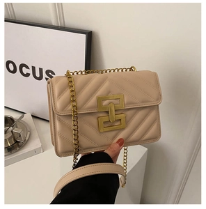 Close-up of beige quilted crossbody bag with golden geometric lock and chain strap