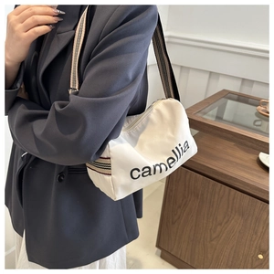 Detail of white nylon pillow bag with black camellia text and striped wide shoulder strap