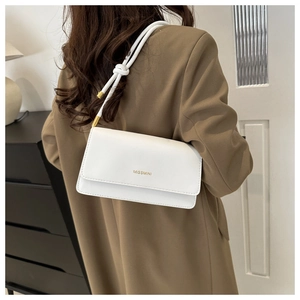 Detail of white minimalist crossbody bag with unique knot shoulder strap and gold hardware