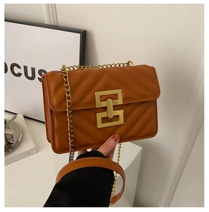 Close-up of caramel quilted leather shoulder bag with gold V-shaped stitch and buckle