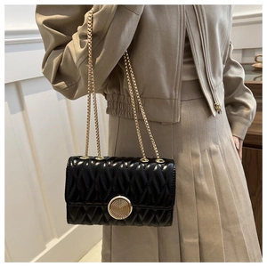 Détail du sac en cuir verni matelassé noir avec une boucle ronde en métal doré