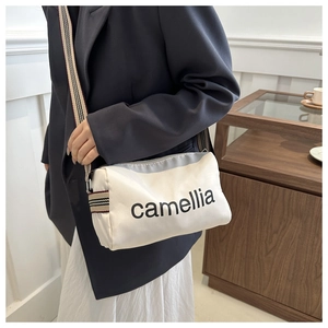 Detail of cream nylon pillow bag with striped strap and camellia print on shoulder