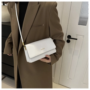 Close-up of a white minimalist leather shoulder bag with gold hardware and logo