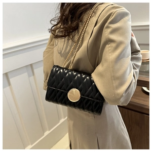 Détail du sac matelassé noir avec fermoir doré en spirale porté par un mannequin