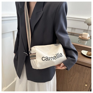 Minimalist beige nylon crossbody bag with camellia print and striped strap on model