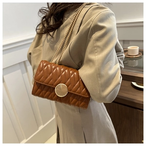 Détail d'un sac à bandoulière matelassé marron avec chaîne dorée et fermoir métallique