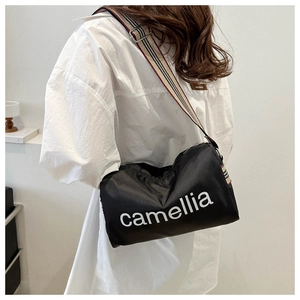 Detail of black nylon crossbody bag with camellia print and striped woven shoulder strap