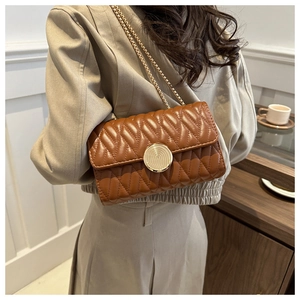 Détail d'un sac en cuir matelassé marron avec une fermeture à loquet doré circulaire