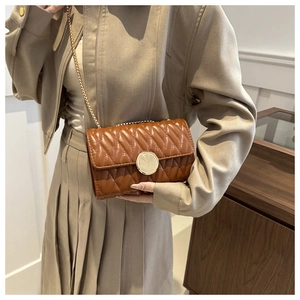 Détail du sac matelassé marron avec fermoir tournant doré et bandoulière chaîne élégante
