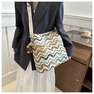 Close-up of colorful wave knit shoulder bag with ethnic strap and plush charm