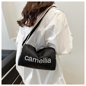 Detail of large black nylon pillow bag with camellia print and colorful striped strap