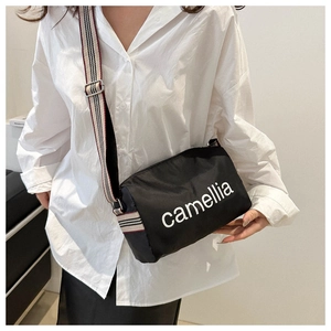 Detail of black nylon pillow bag showing camellia lettering and striped wide strap