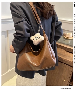 Detail of soft brown PU leather hobo bag with plush smiley charm and pleated texture