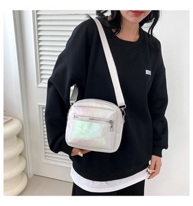Detalle de bolso bandolera irisado con acabado plateado holográfico y bolsillo con cremallera