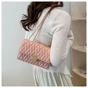 Détail d'un sac bandoulière rose matelassé avec chaîne dorée et fermoir métallique rond