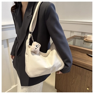 Close-up of minimalist beige PU leather crescent tote bag with cute plush puppy charm