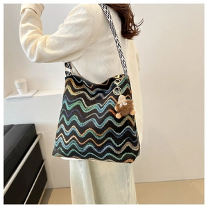 Detail of black wave-pattern knit tote bag with wide strap and plush monster charm