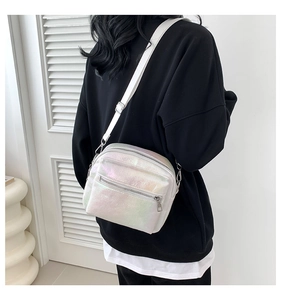 Detalle del bolso bandolera blanco iridiscente con cremalleras plateadas y textura suave