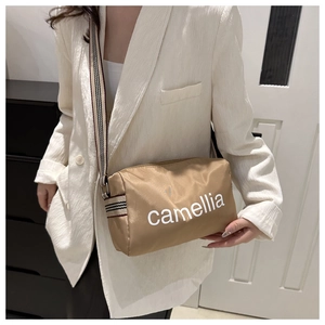 Detail of a brown nylon crossbody bag with striped wide strap and camellia text