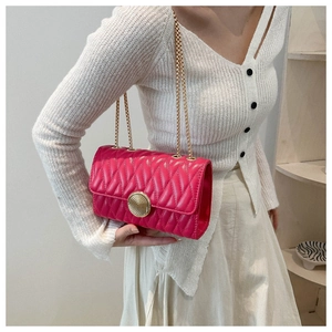 Détail du sac bandoulière matelassé rouge rose avec fermoir doré rond et chaîne chic