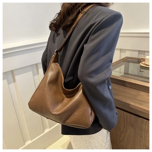 Brown soft PU leather hobo bag worn by model in a stylish indoor setting