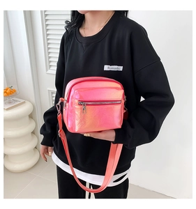 Close-up of pink iridescent crossbody bag with double zippers and canvas strap on model