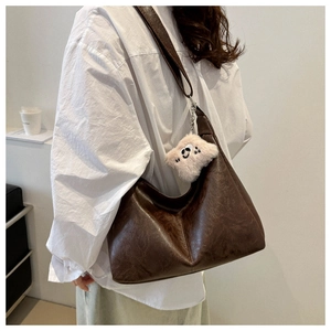 Detail of dark brown vintage hobo bag with textured faux leather and plush smiley charm