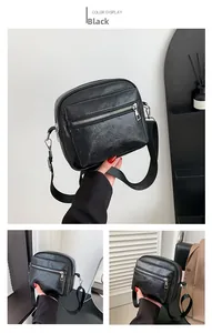 Detalle de bolso bandolera negro con cremalleras plateadas y correa de nailon ajustable