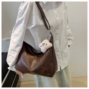 Detail of dark brown faux leather hobo bag with vintage texture and plush ghost charm
