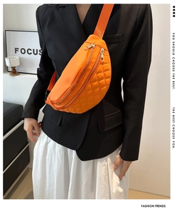 Macro shot of bright orange quilted nylon saddle bag with parallel golden zippers