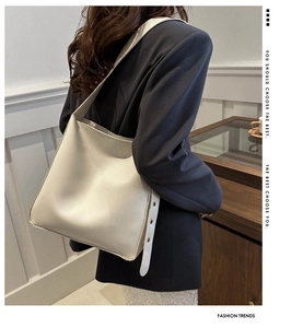 Off-white PU leather tote bag worn by model showing side view and metal eyelet details