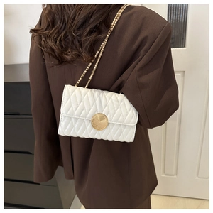 Sac bandoulière matelassé blanc sur mannequin avec chaîne dorée et boucle chic en métal
