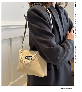 Close-up of beige crossbody bag with chunky acrylic chain and FASHION label detail