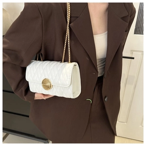 Gros plan d'un sac à bandoulière matelassé blanc avec un fermoir doré en spirale