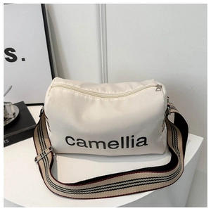 Close-up of cream nylon crossbody bag featuring Camellia text and striped wide strap