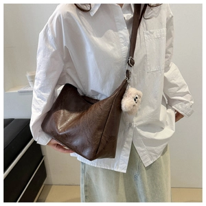 Detail view of large dark brown PU leather shoulder bag with white plush dog pendant