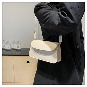 Close-up of minimalist cream white leather square crossbody bag worn by a model