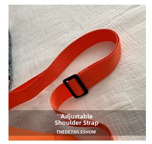 Detail of adjustable orange woven shoulder strap with black buckle and durable nylon texture