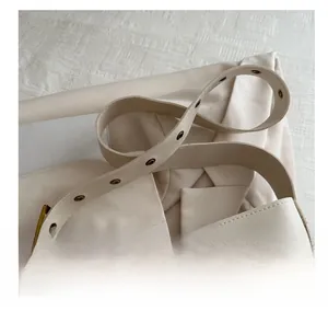Detail of cream PU leather shoulder strap with adjustable metal eyelets and bronze buckle