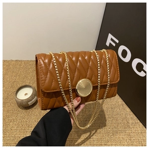 Détail du sac matelassé marron avec fermoir tournant doré et bandoulière à double chaîne