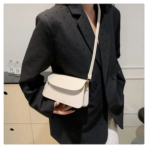 Detail of minimalist ivory leather crossbody bag with flap and fine stitching on a model