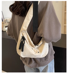 Detail of creamy tote bag with black wide strap and braided rope zipper pull accents
