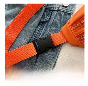 Detail of high-quality black plastic buckle and thickened woven strap on orange waist bag
