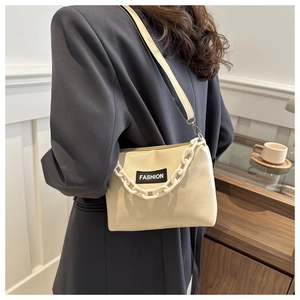 Close-up of beige leather crossbody bag featuring resin chain and FASHION logo tag