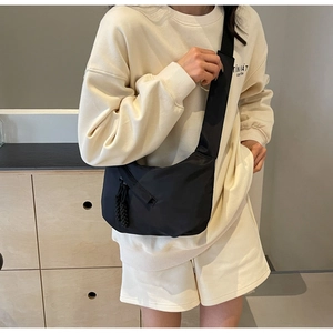 Detailansicht der schwarzen Messenger-Bag aus Nylon mit gewebten Reißverschluss-Anhängern