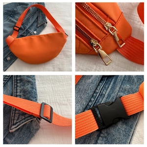 Close-up of orange quilted waist bag details with zippers, strap buckle and clasp
