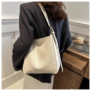 Detail view of cream white minimalist leather bucket bag with wide shoulder strap